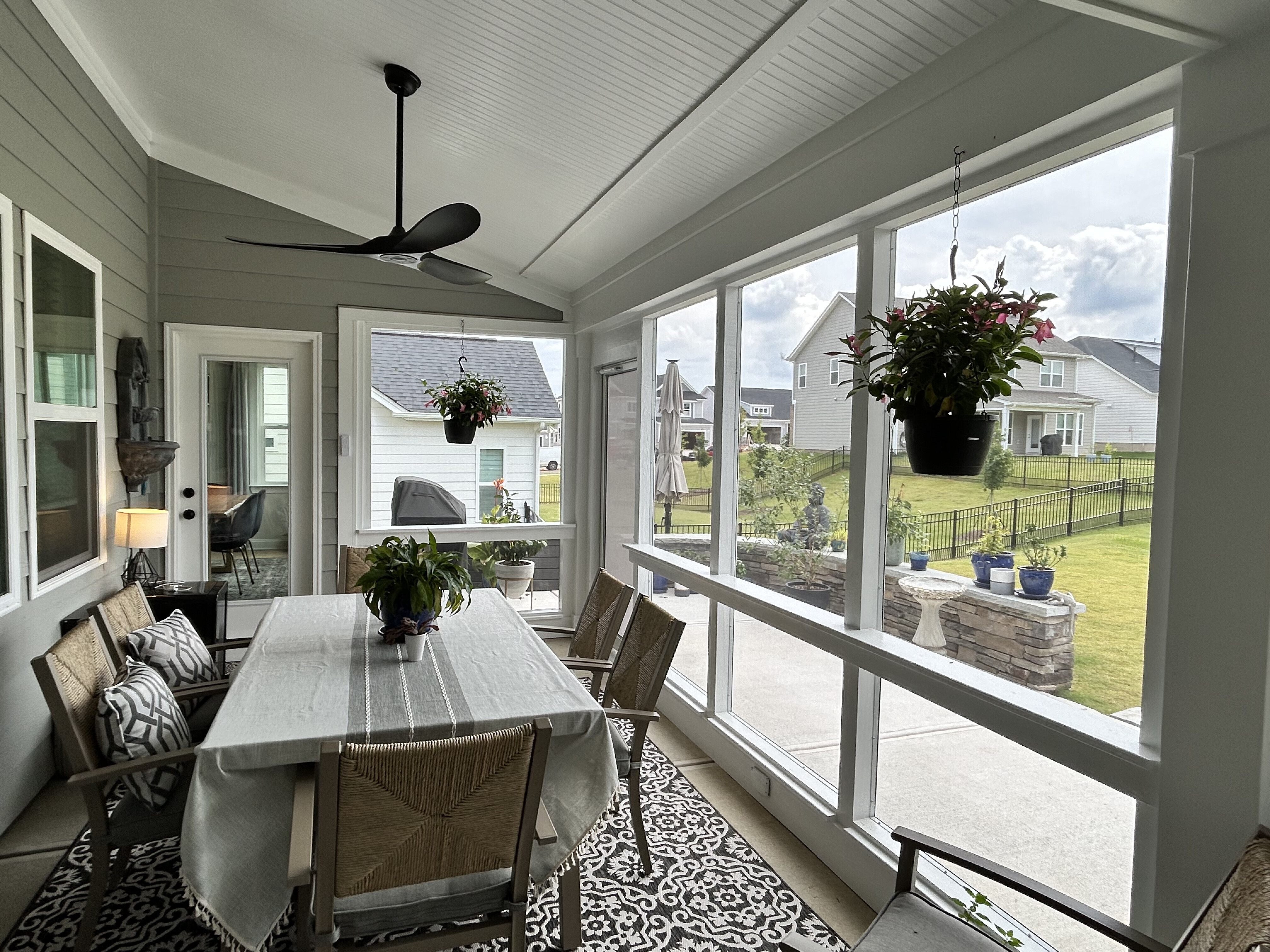 Inside view of a screened porch with a dining table, ceiling fan, and outdoor rug in Charlotte, NC.
