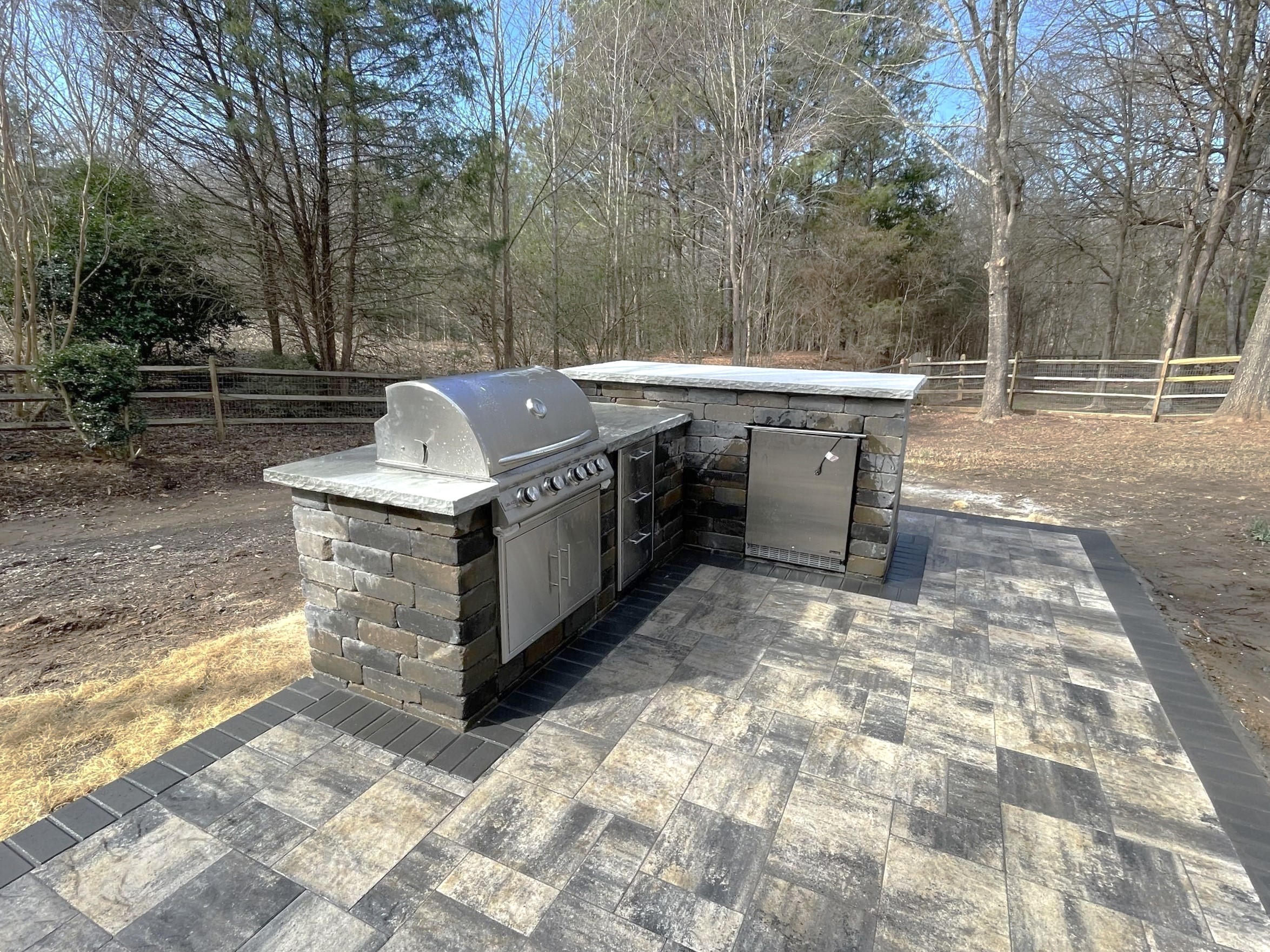 Paver patio with a custom outdoor kitchen featuring a grill and appliances in Charlotte, NC.