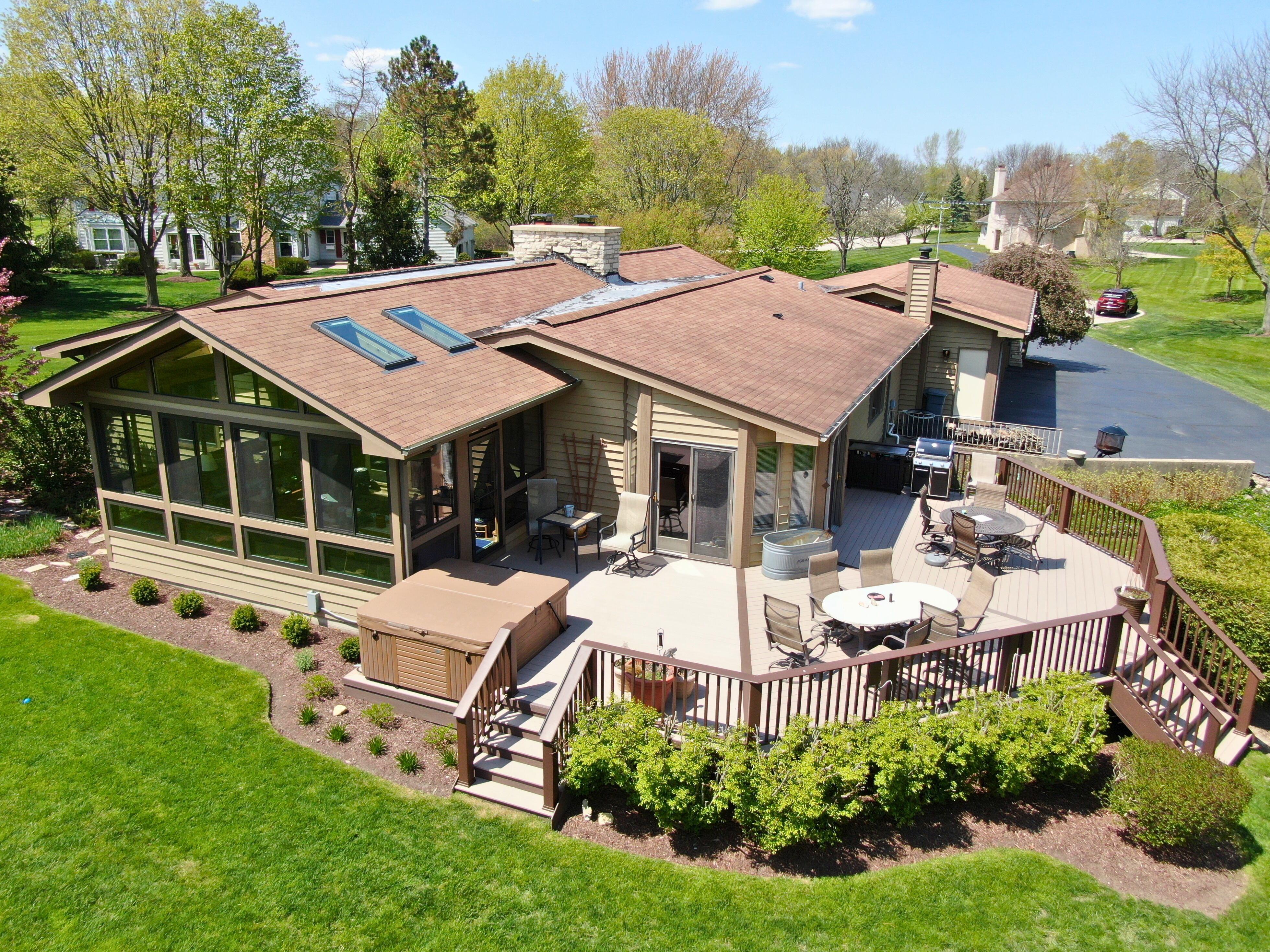 Aerial view of a stunning outdoor living space featuring a custom sunroom and huge timbertech deck. Designed and built by Archadeck of Chicagoland-Naperville.