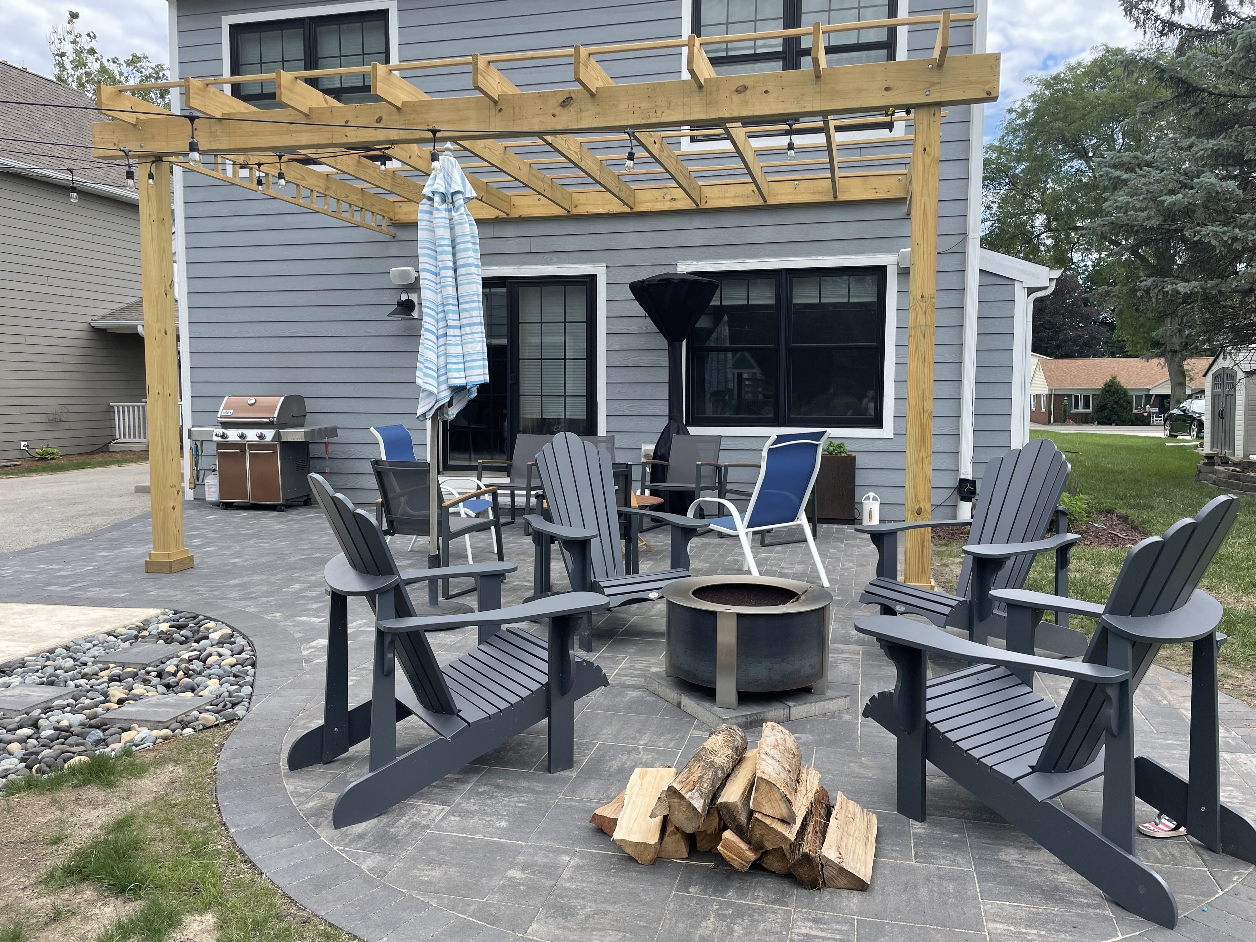 Custom paver patio with a wood pergola, fire pit, and lounge chairs in Bolingbrook, IL.