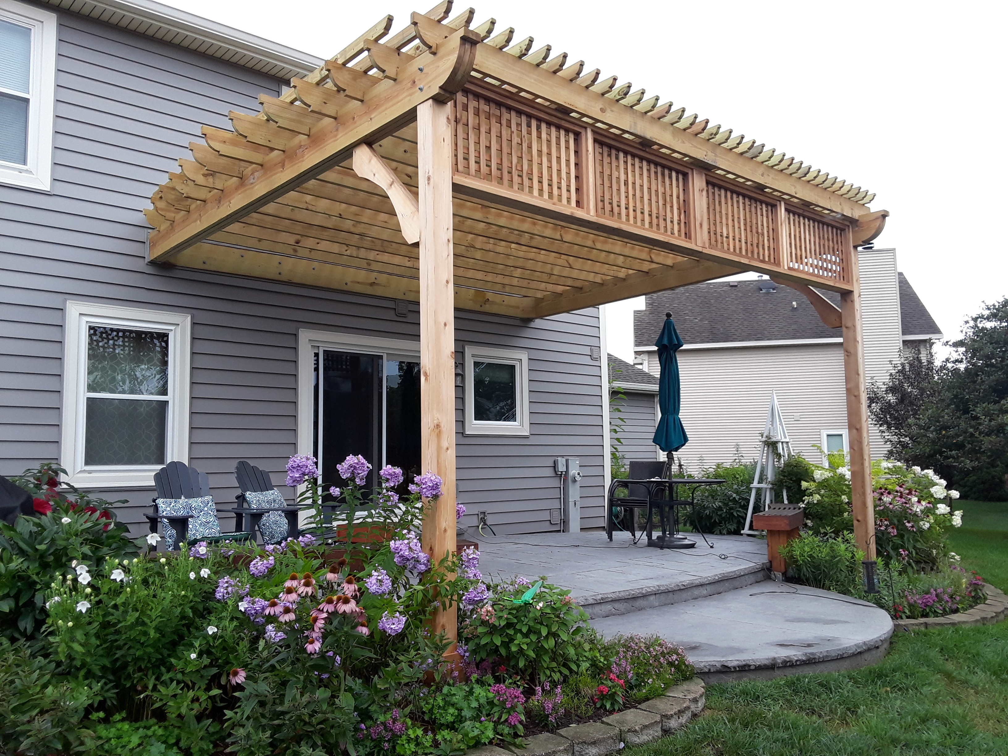 Custom wood pergola featuring vertical slats, custom bracing, and gorgeous views of spring flowers in Naperville.