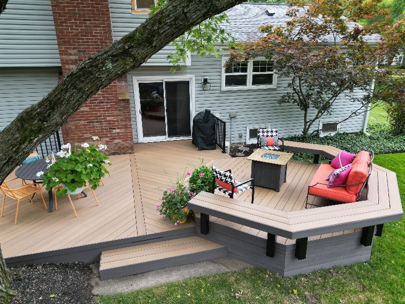 Custom multi-level composite deck with built-in seating, brick chimney accent, and integrated fire pit, designed by Archadeck of Chicagoland.