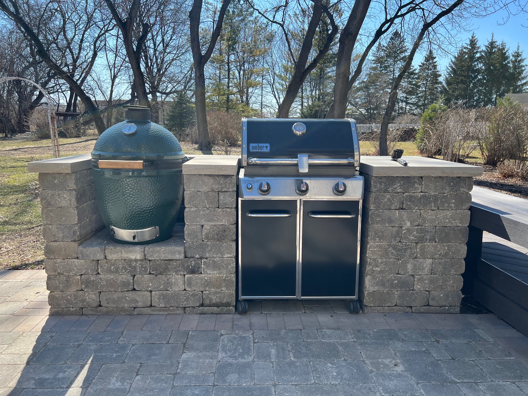 Custom paver grill surround with a green egg and weber grill by archadeck.