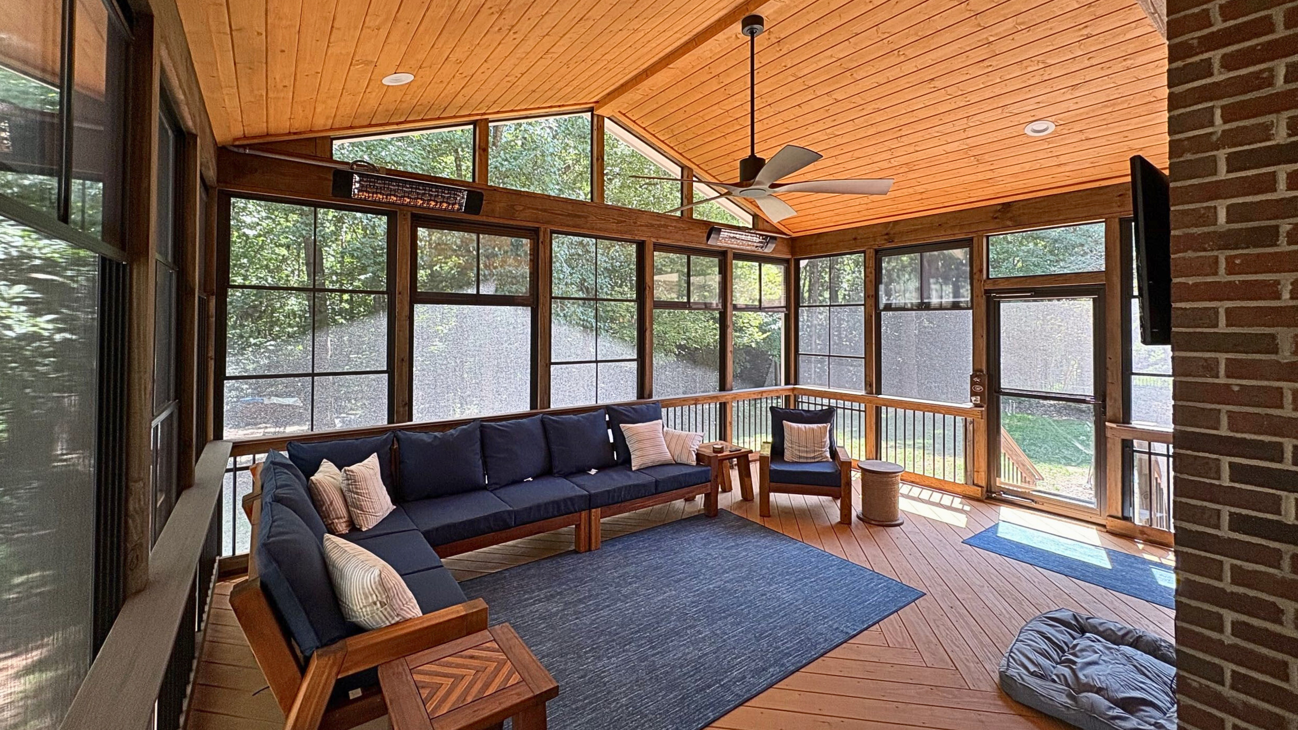 Inside of a custom Archadeck porch with outdoor furniture, a rug, and outdoor heaters.