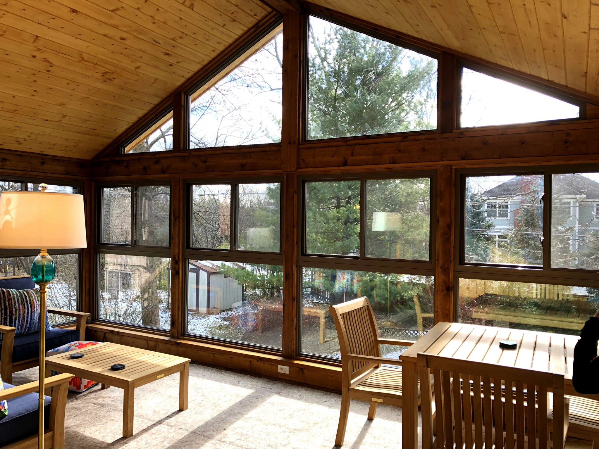 Gorgeous view of inside a sunroom with floor to ceiling glass windows by Archadeck.