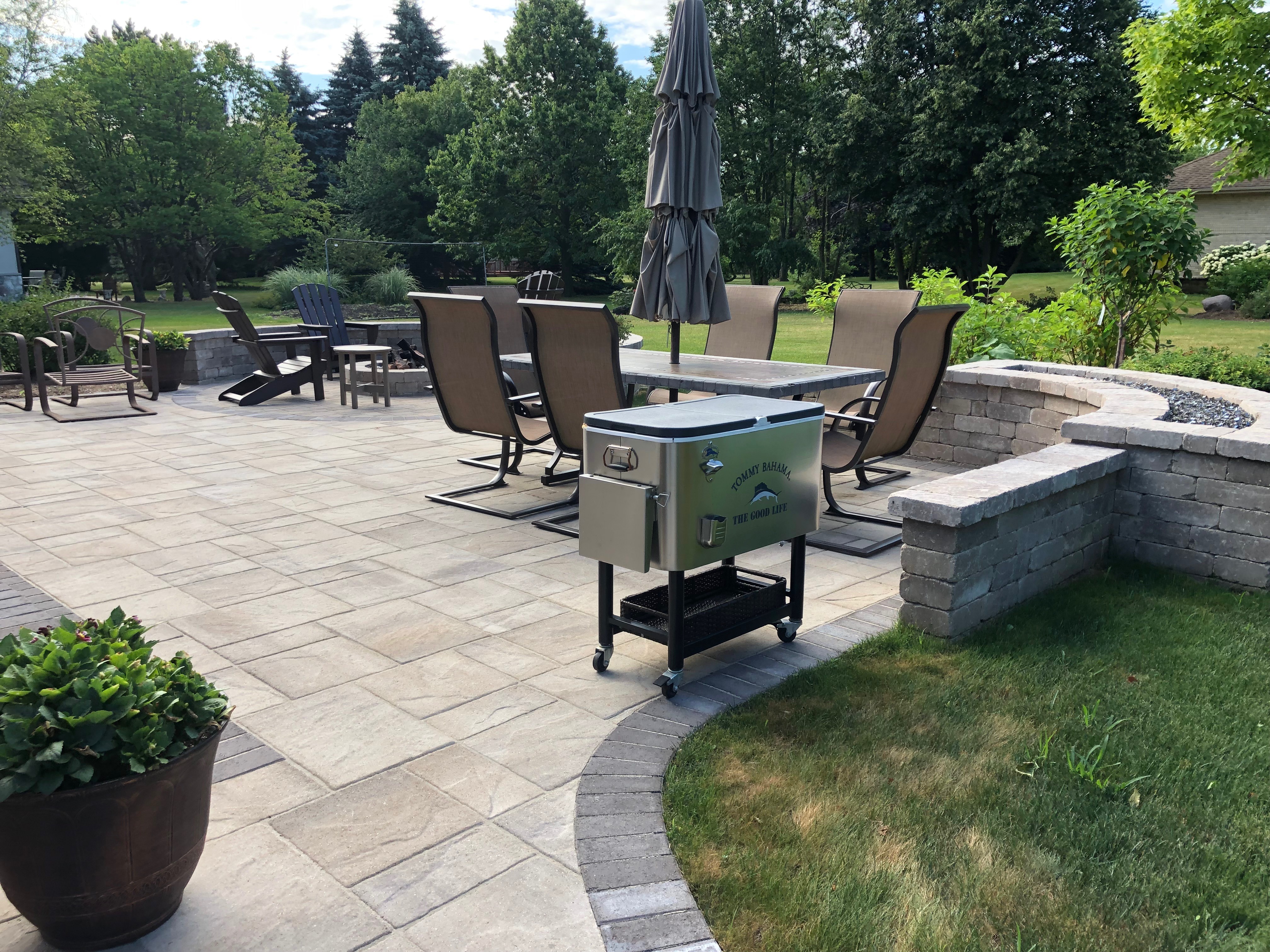Custom paver patio with outdoor furniture and built in curved firepit by Archadeck.