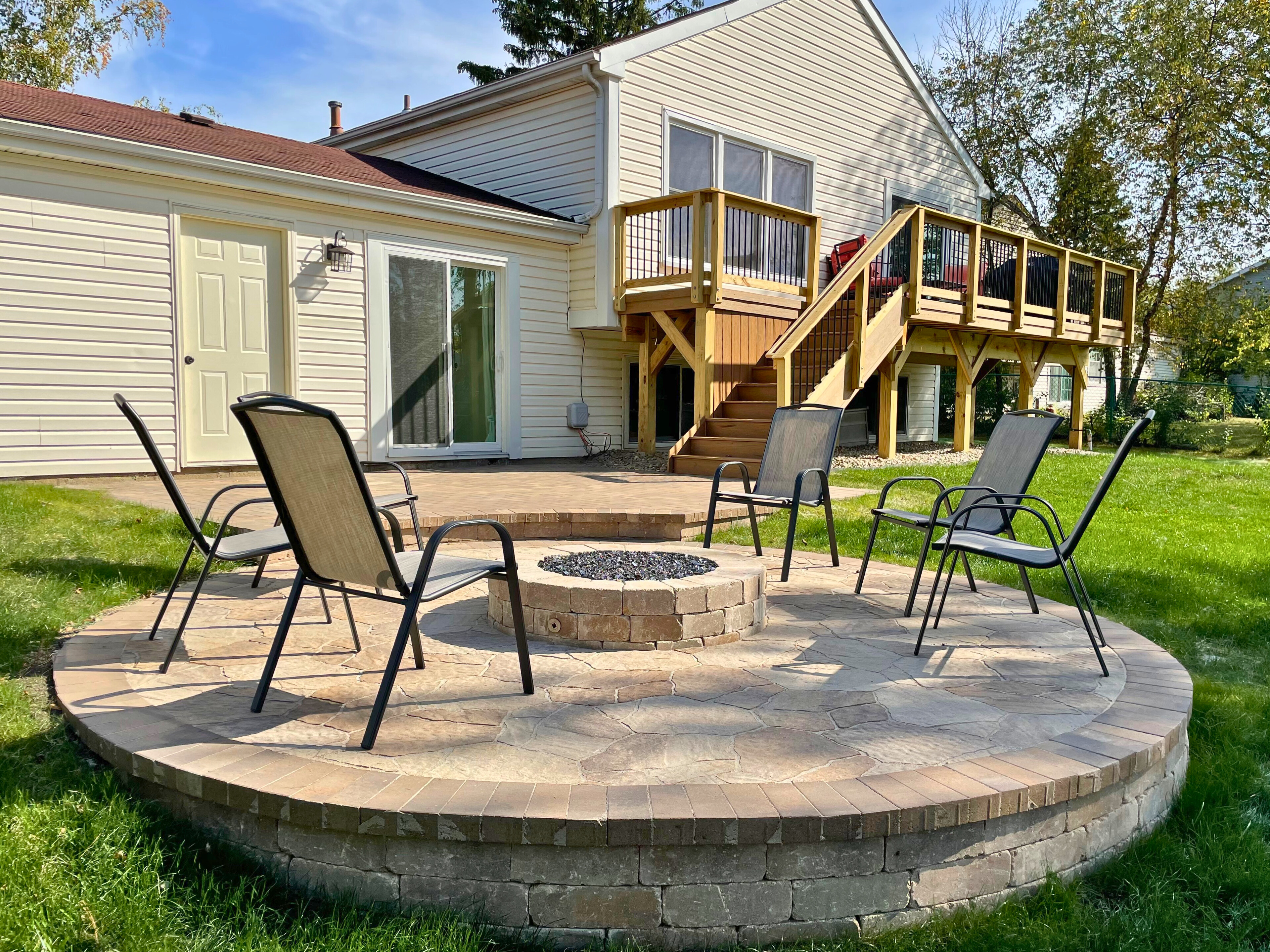 Paver patio and firepit with stairs leading up to a composite deck in Lake Zurich, IL.