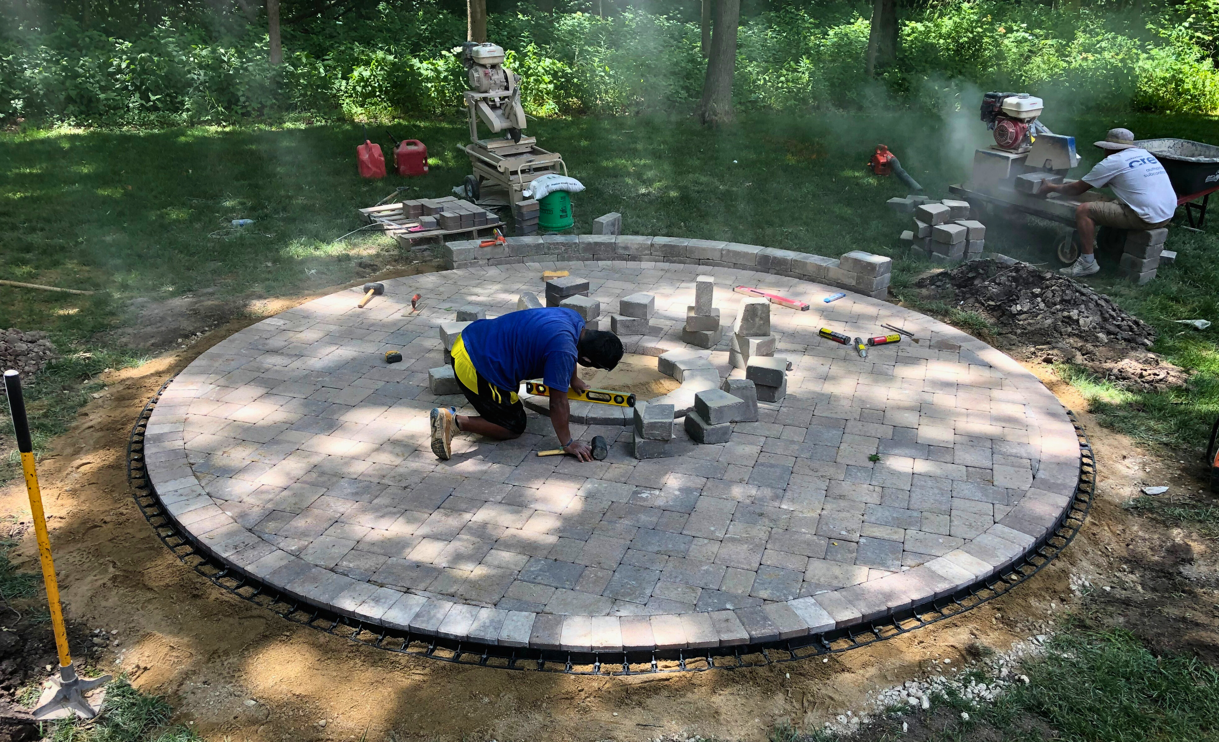 Paver patio installers installing a fire pit and circle patio.