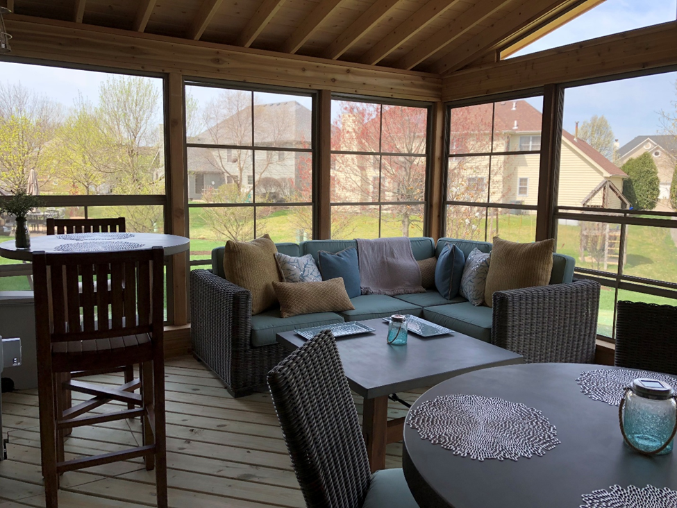 Inside a custom Archadeck porch in Aurora, IL. featuring 4-track windows and lounge furniture.