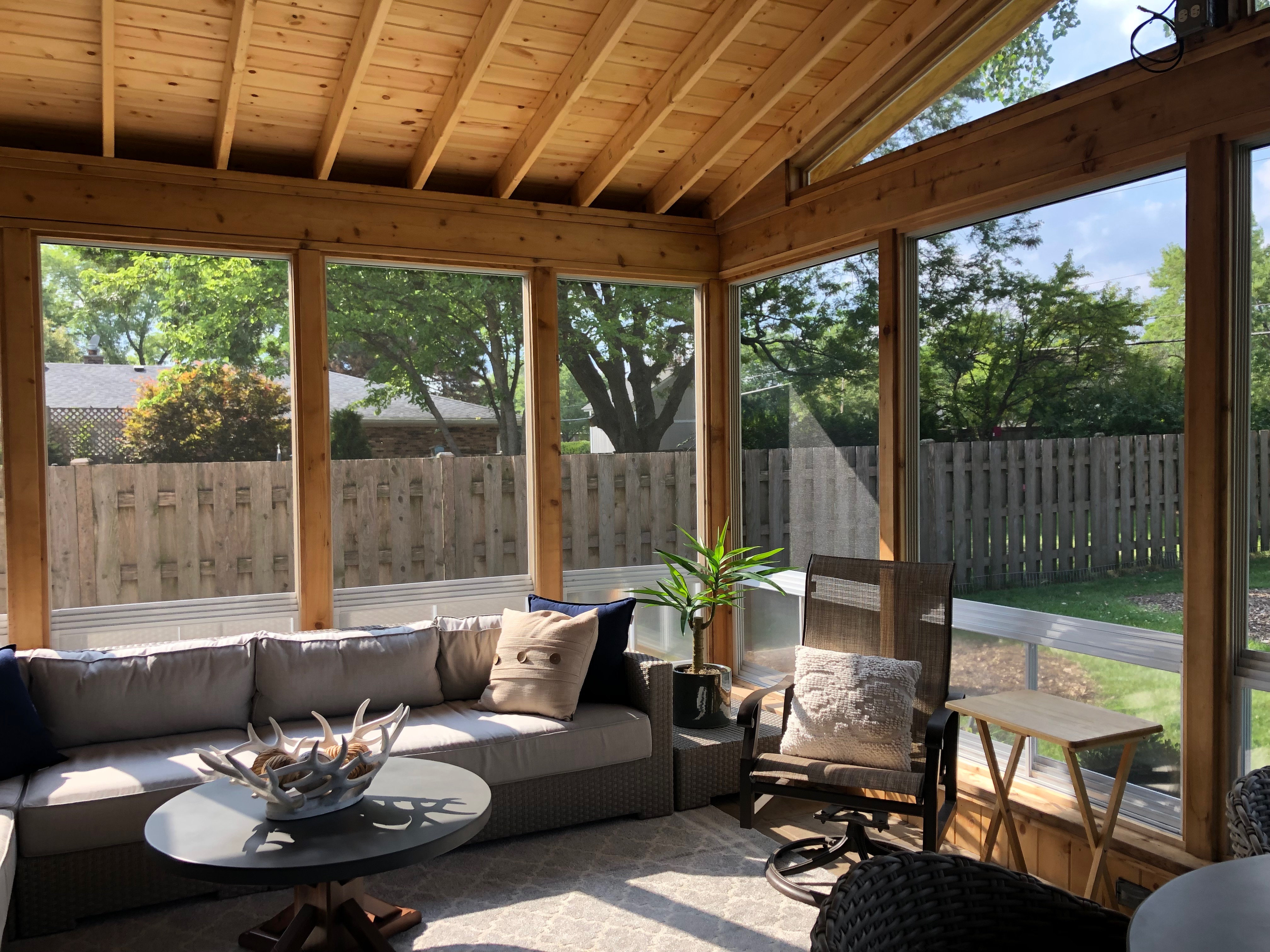 Inside of a custom porch in Plainfield, IL with 4-track windows and open rafteres.