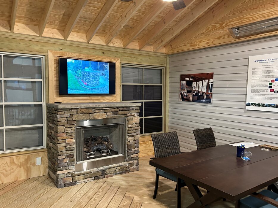 Archadeck of Charlotte Design Center Porch Display with fireplace, tv, and dining table