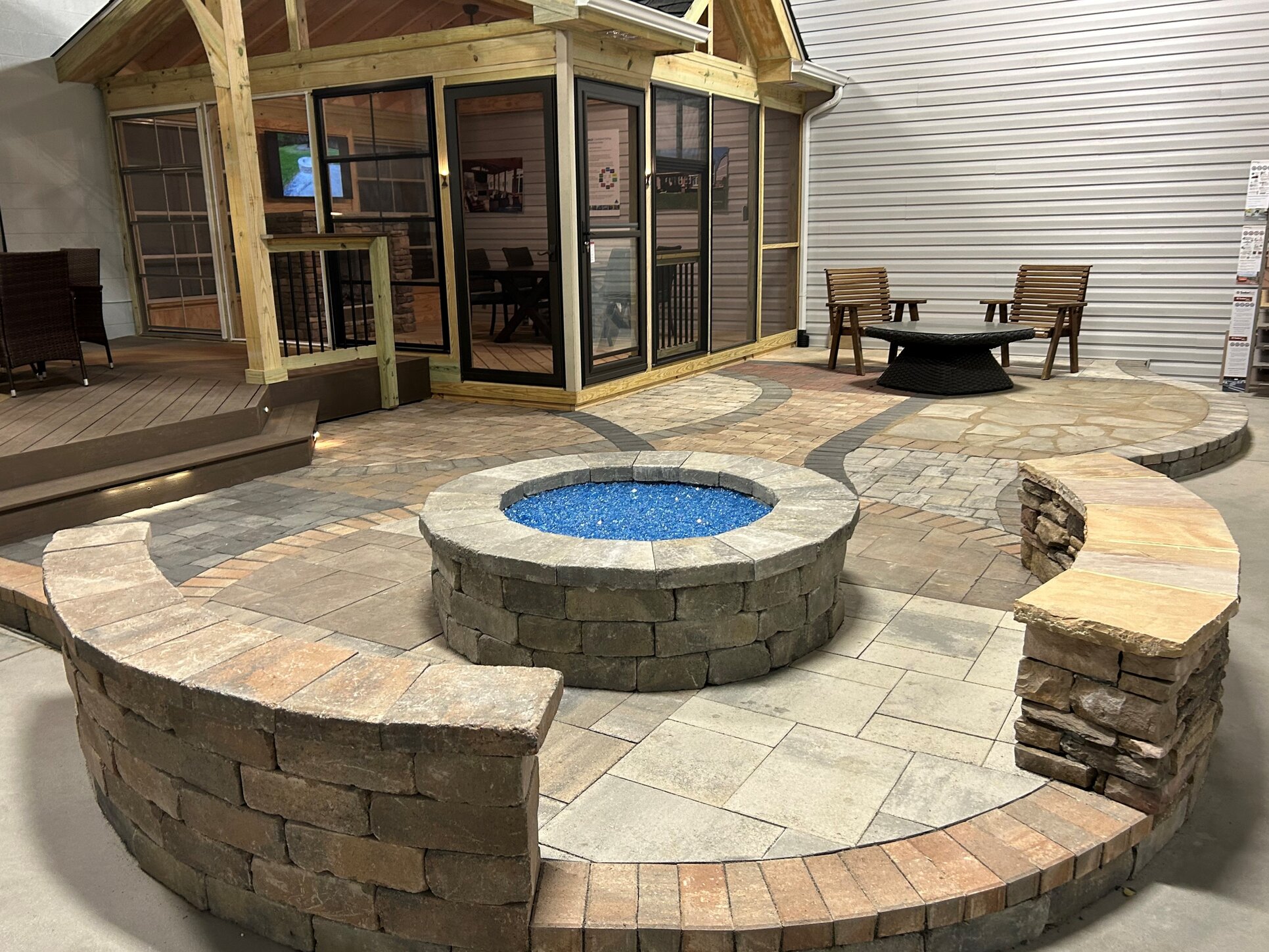 Paver patio display in archadeck of charlotte showroom featuring seat walls, a fire pit, and a peak at the porch display.