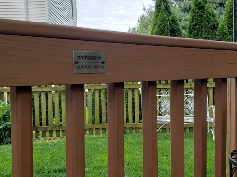 Outdoor wooden railing with Archadeck logo