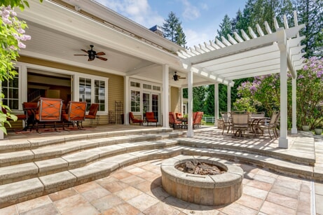 A patio with stairs, a fire pit, and dining area outside of a home in Johns Creek, Georgia