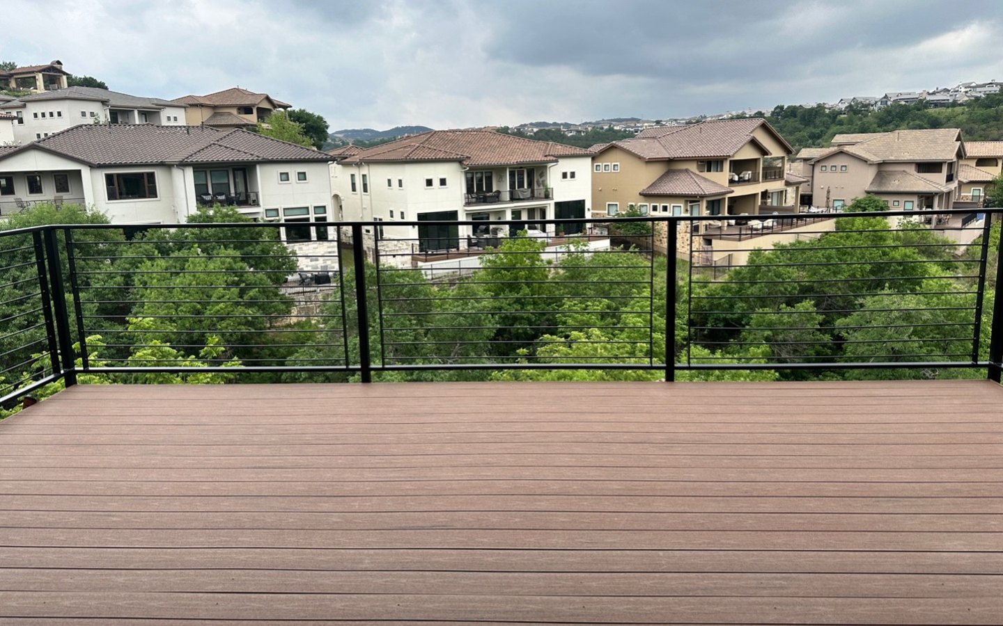 A deck with a fence and trees in the background

Description automatically generated