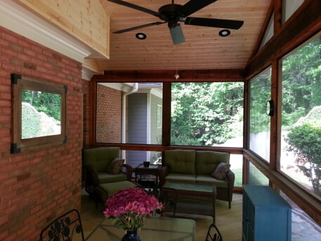 screened porch with sitting area and flowers on the table
