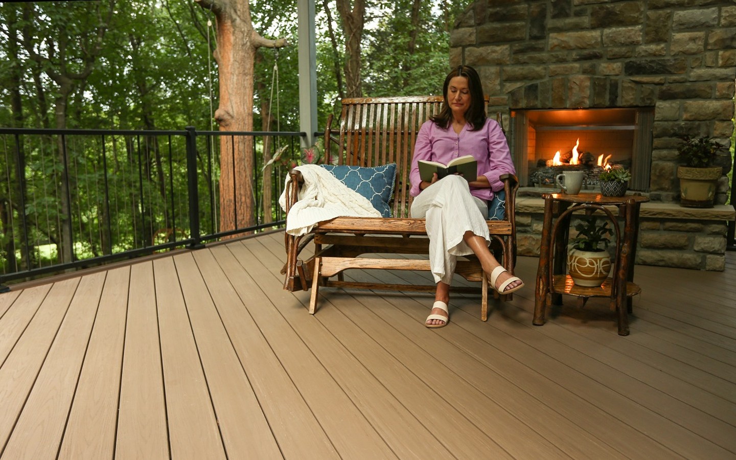 A person sitting on a deck reading a book
Description automatically generated