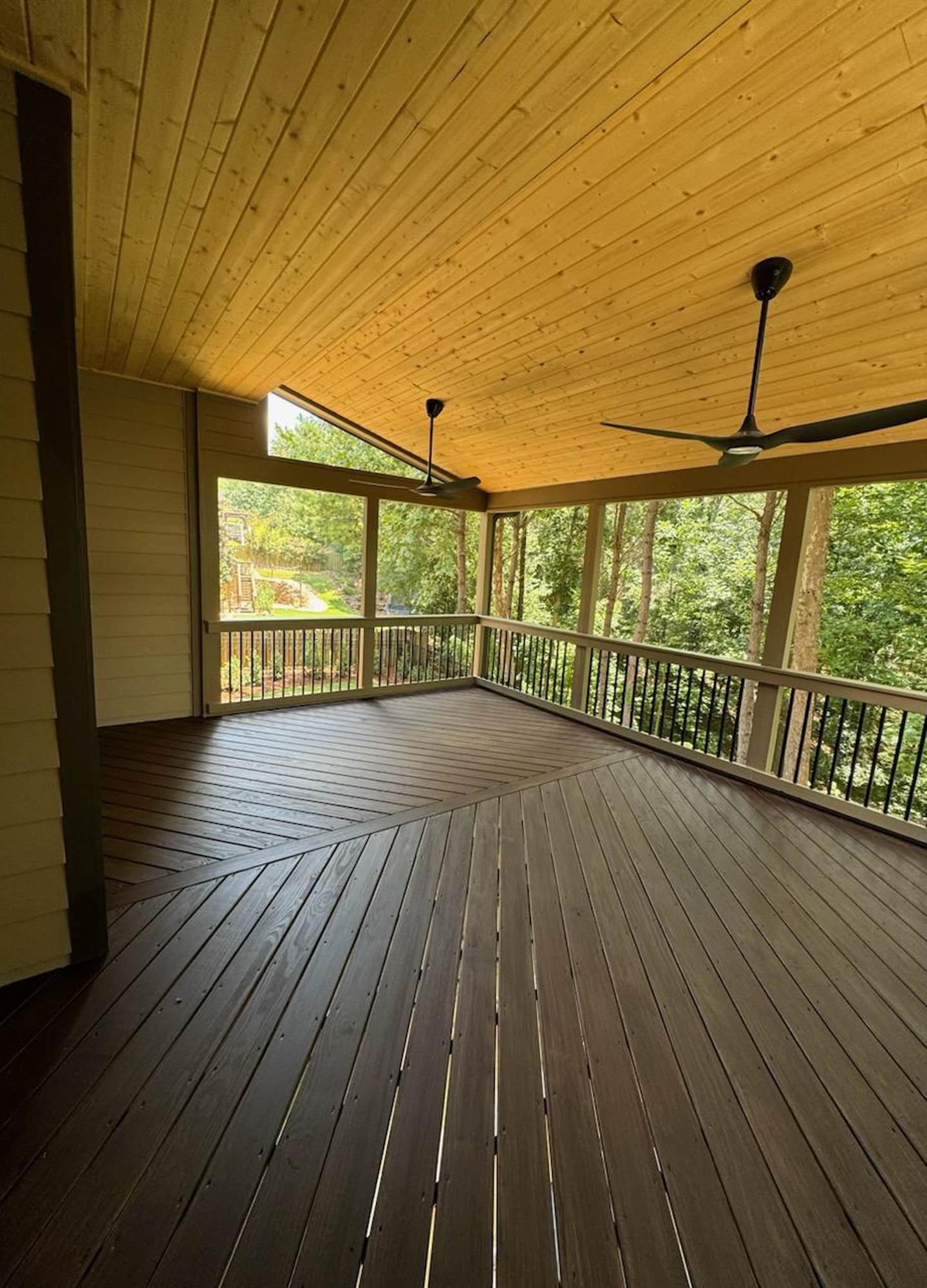 A deck with a ceiling fan and trees

Description automatically generated