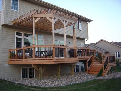 Attached wood pergola follows shape of deck