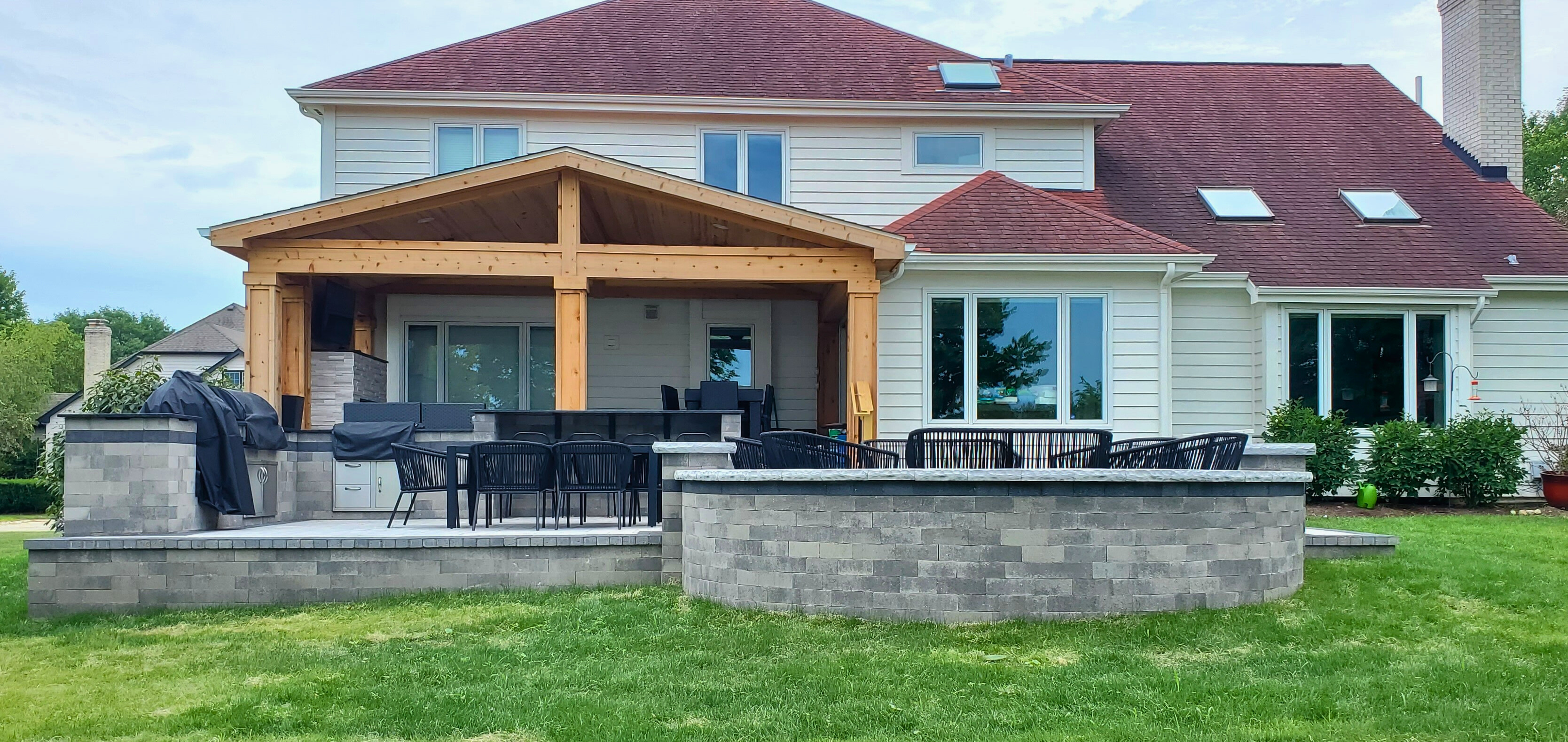 Backyard retreat designed and built by Archadeck of Naperville with paver patio, outdoor kitchen, fire pit, and covered porch. 