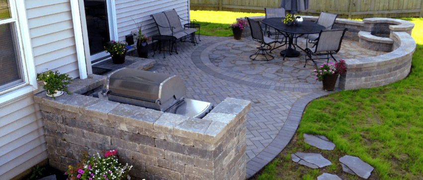 Paver patio with grill surround, custom inset fire pit on the back of a suburban home.