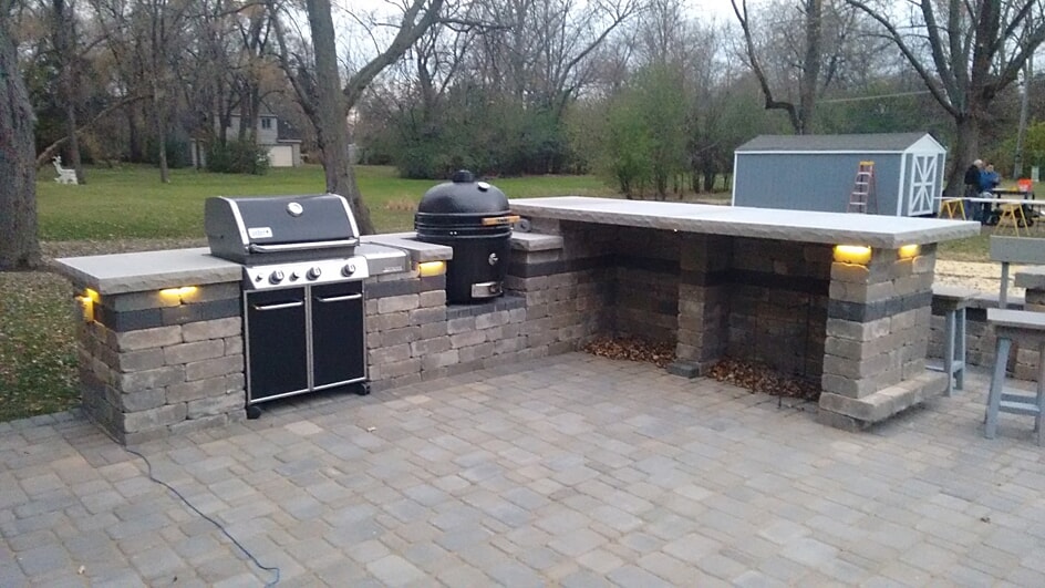 Outdoor Kitchen on a paver patio with a grill, green egg, and custom bar.