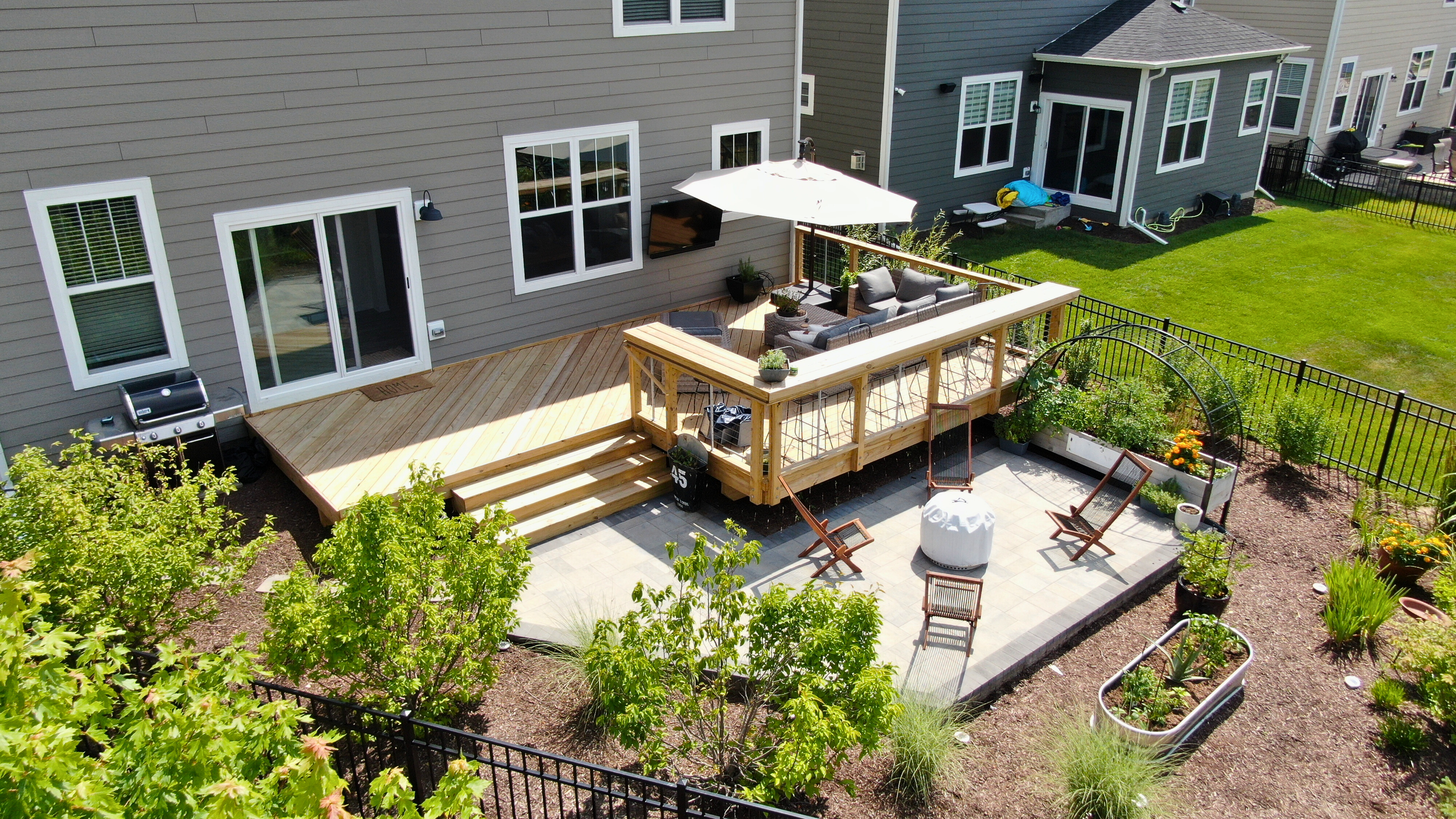 An aerial view of a new multi-level wood deck and paver patio, built by a professional deck builder in Woodridge IL.
