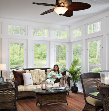 four season room with lots of windows and woman sitting on couch