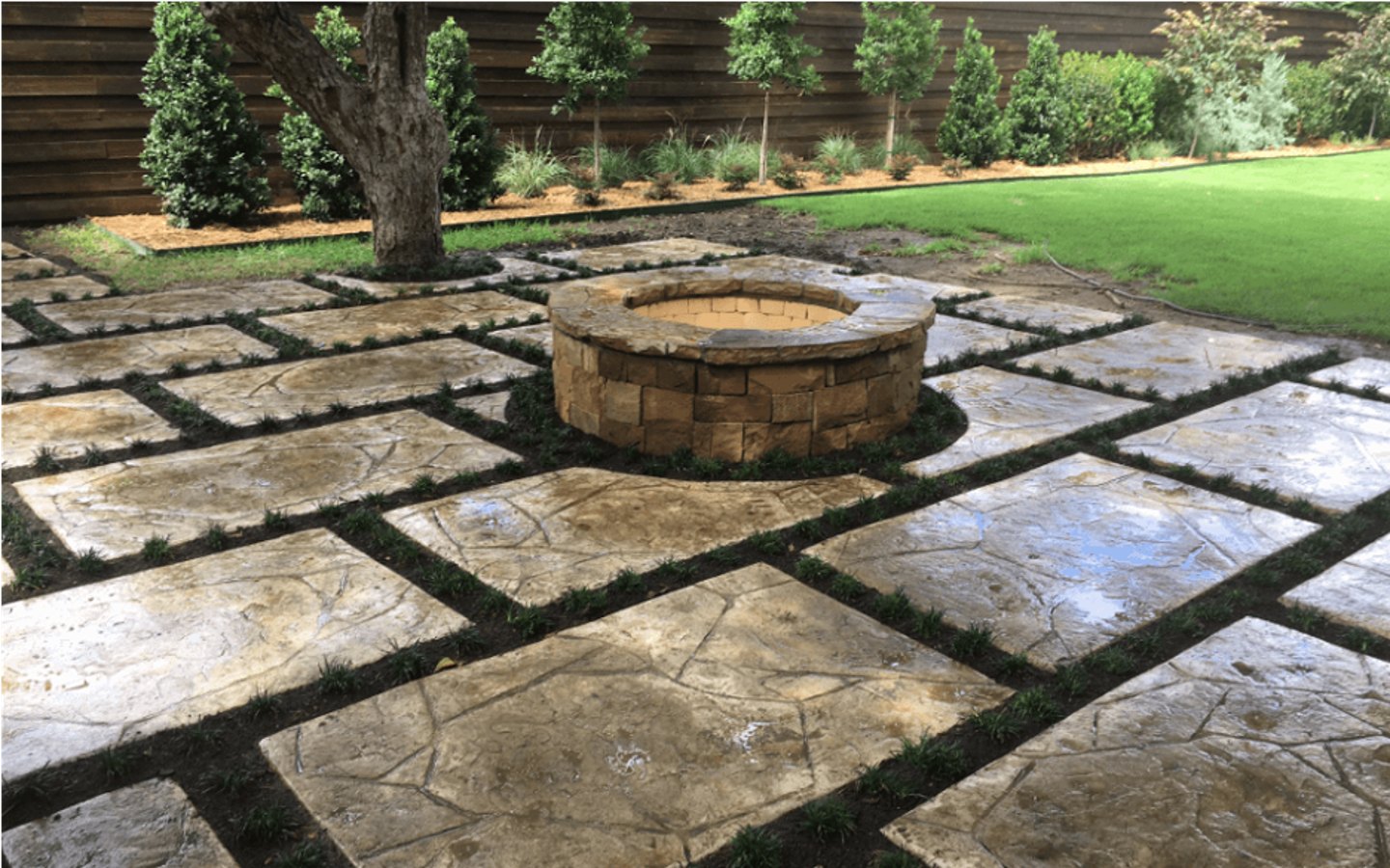 A stone patio with a fire pit
Description automatically generated