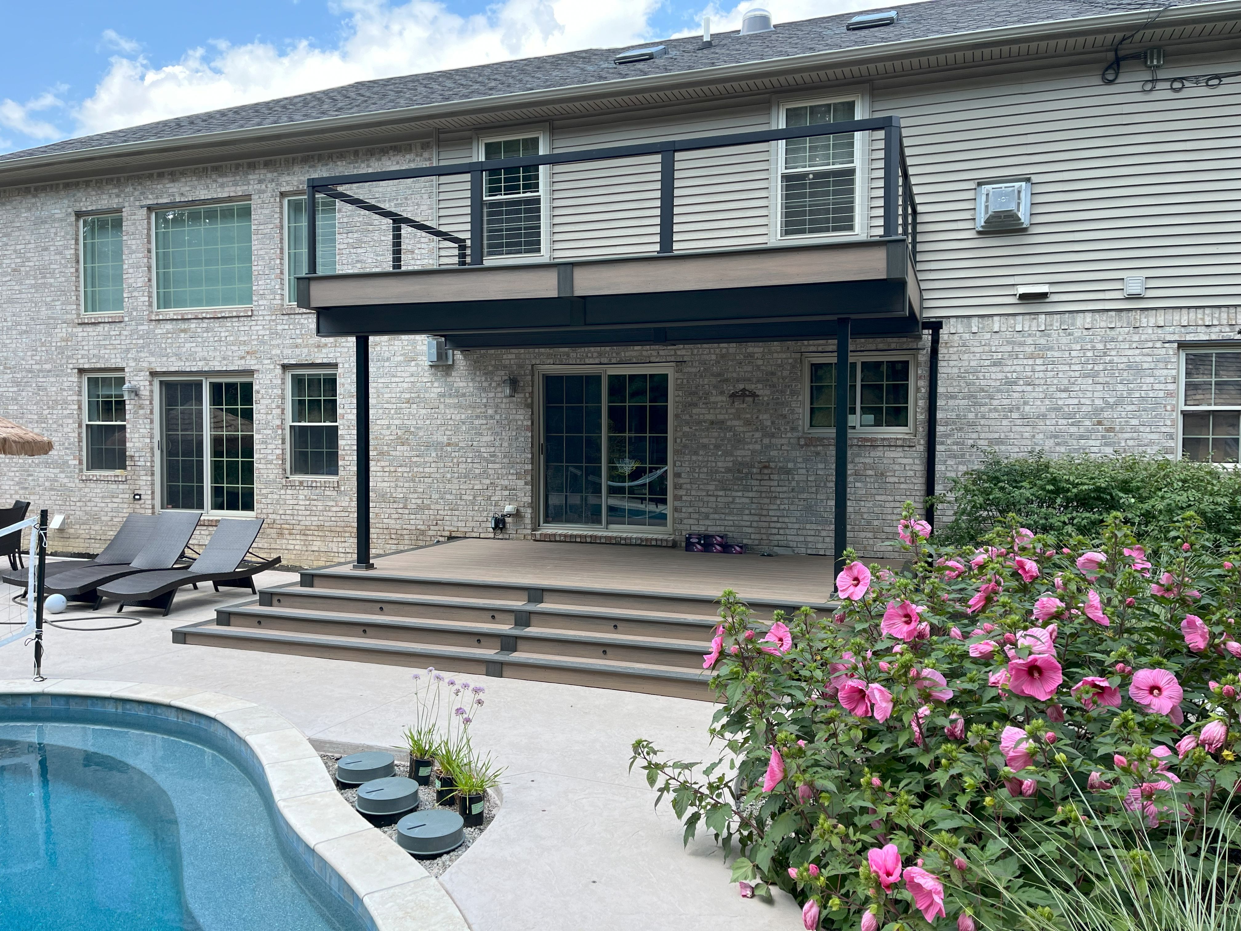 deck off of brick house with pool
